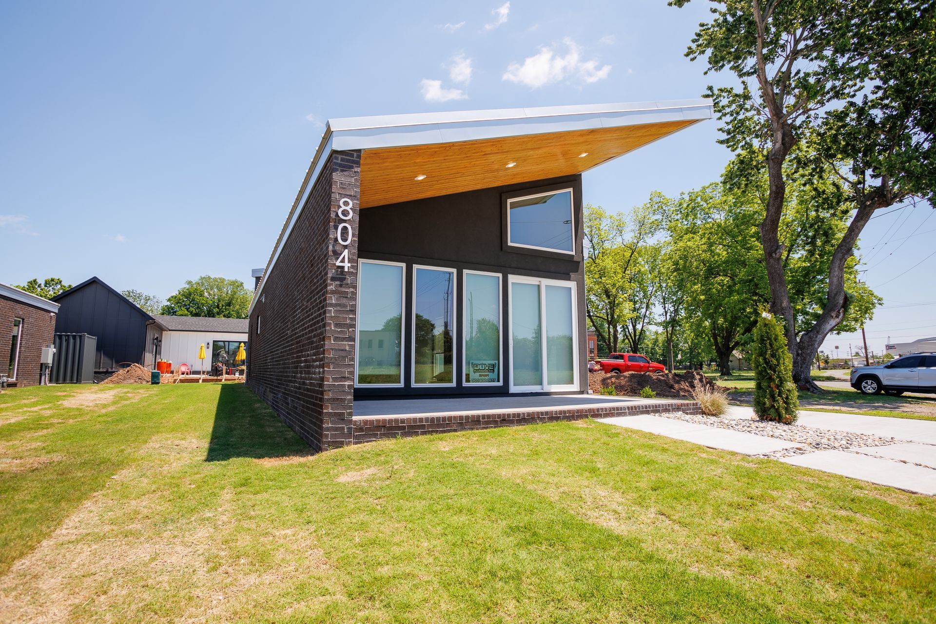 A small house with a lot of windows is sitting on top of a lush green field.