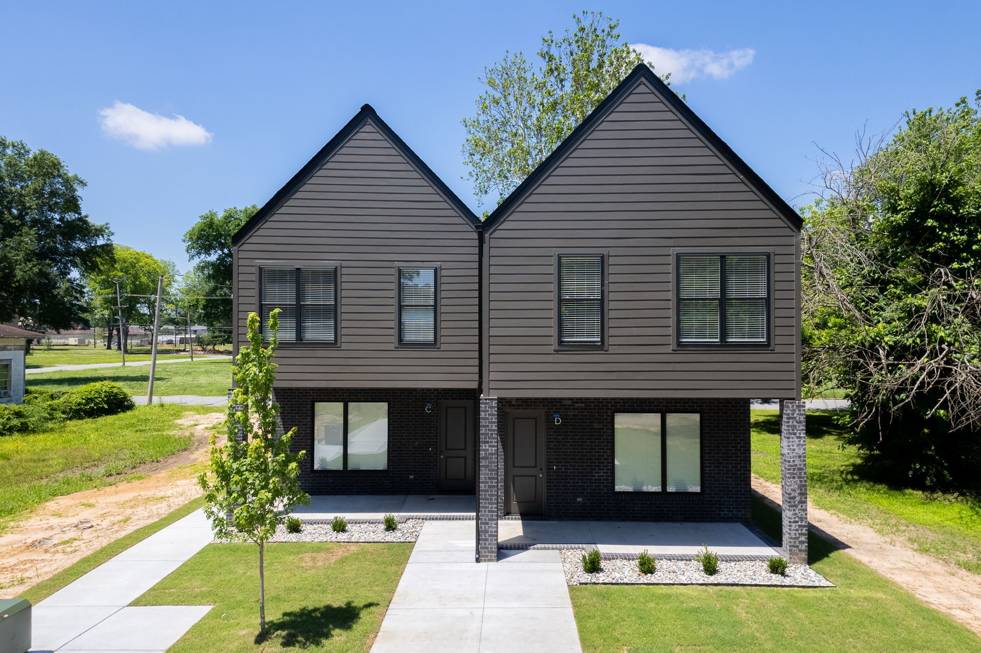 A couple of houses sitting next to each other on top of a lush green field.