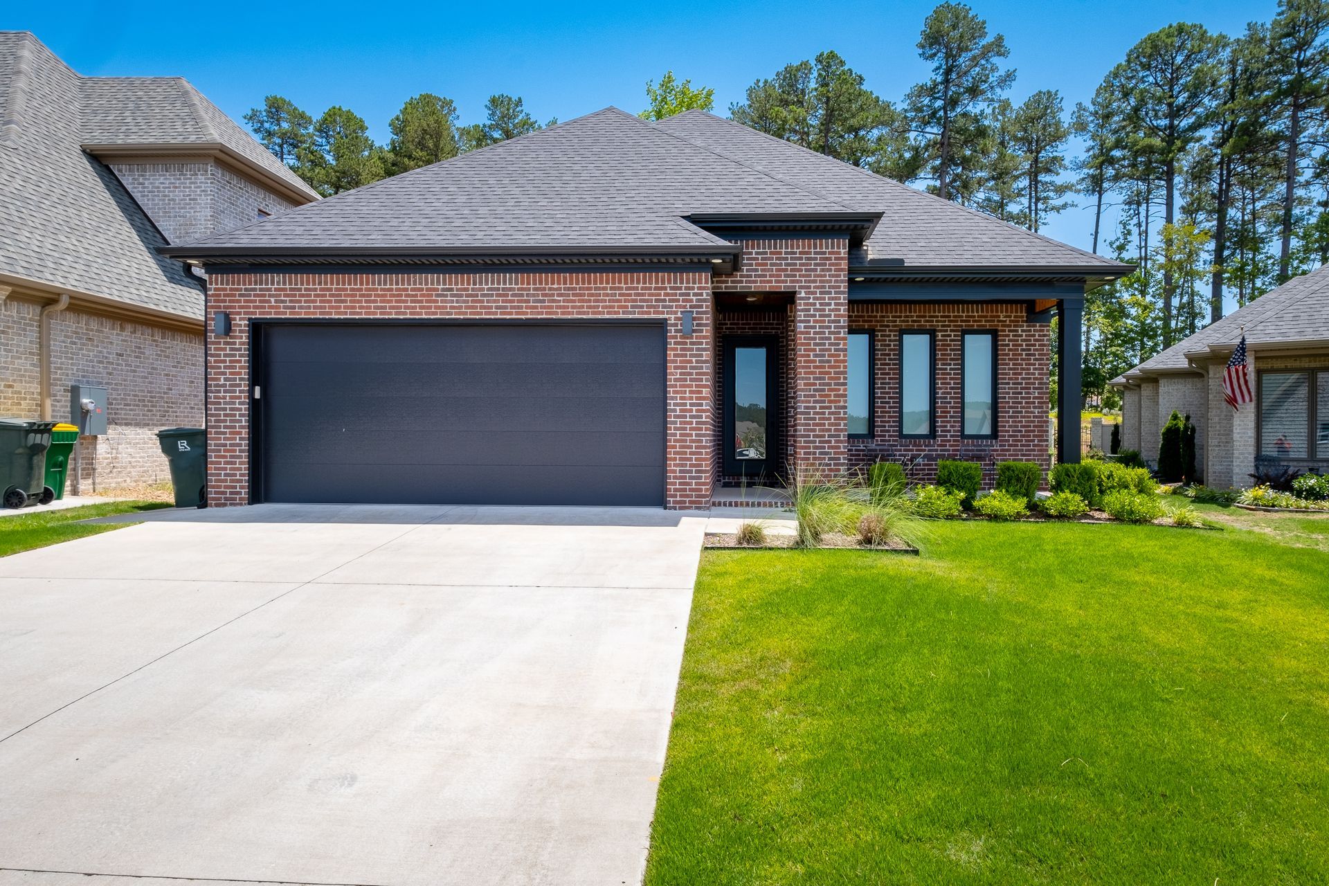 A brick house with a black garage door and a lush green lawn