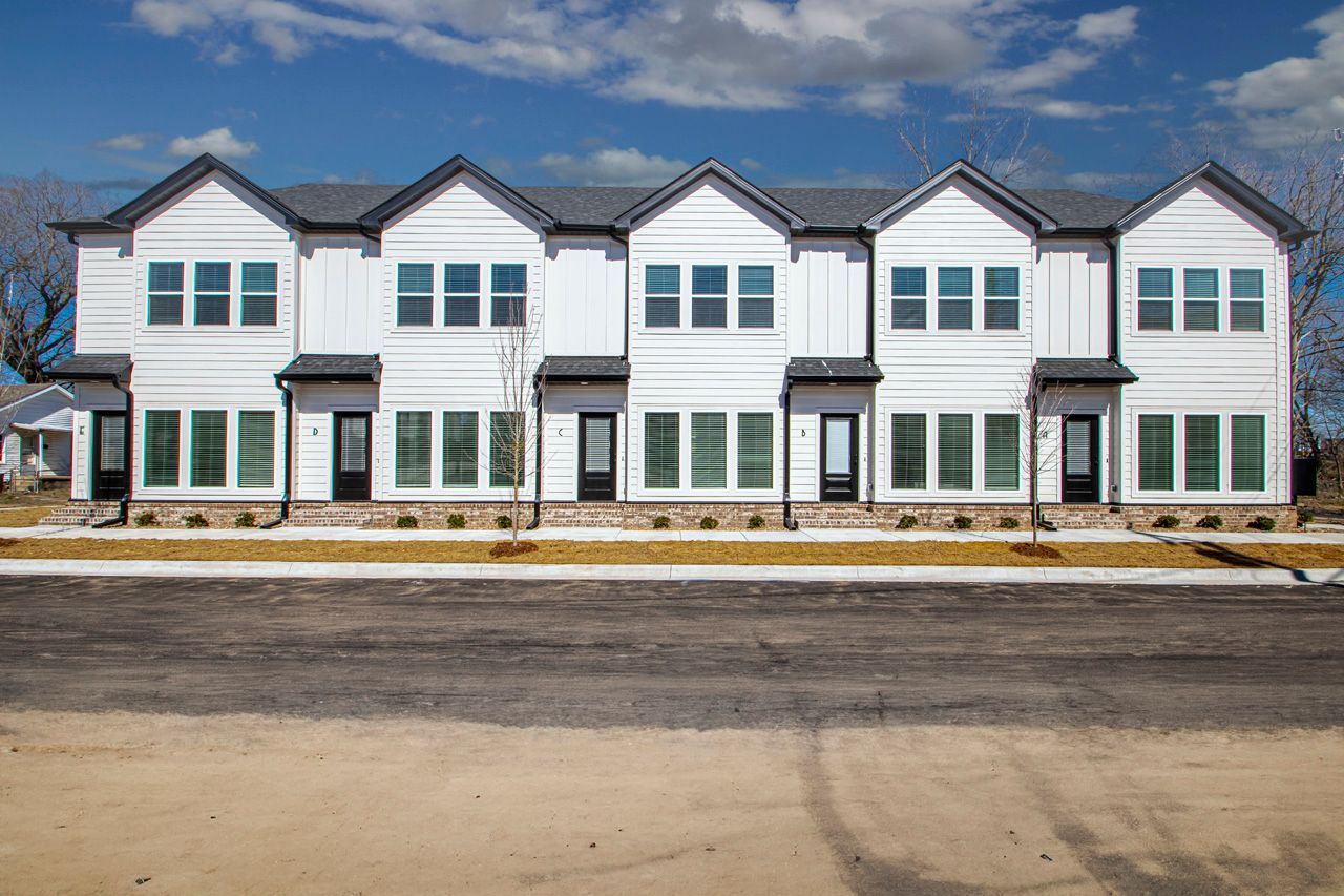 A row of white townhouses with a lot of windows on a sunny day.