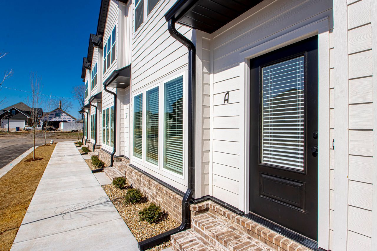 A row of white houses with black doors and windows on a sunny day.