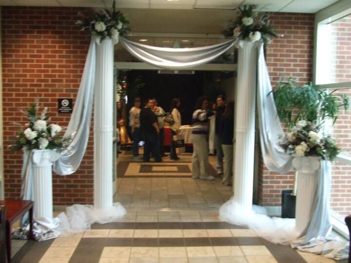 A hallway decorated with white columns and flowers