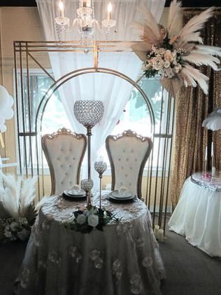 A couple of chairs sitting at a table with plates and candles on it.