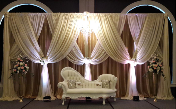 A white couch is sitting in front of a large curtain.