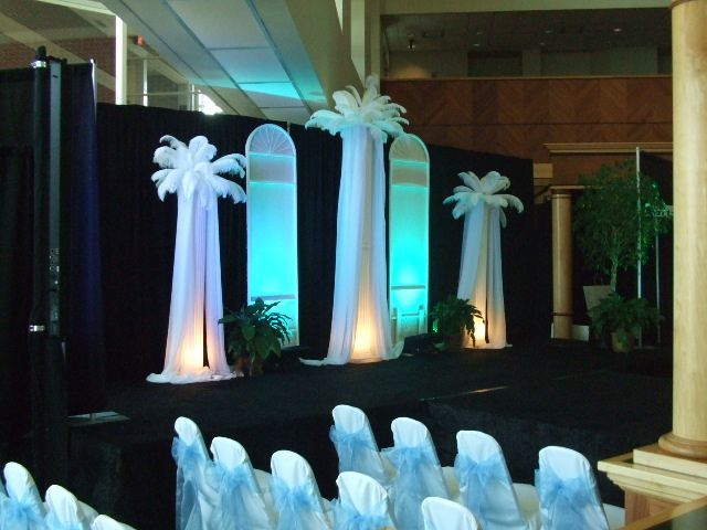 A row of chairs in front of a stage with palm trees in the background