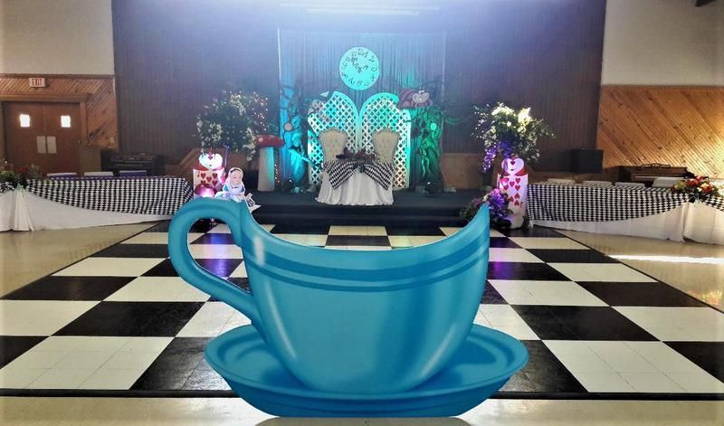 A blue cup and saucer on a checkered floor in a room.