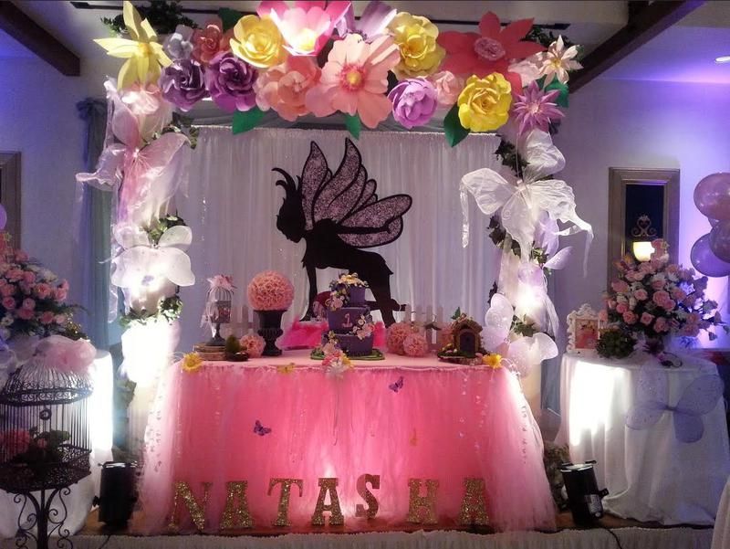 A table decorated with flowers and balloons with the name natasha on it
