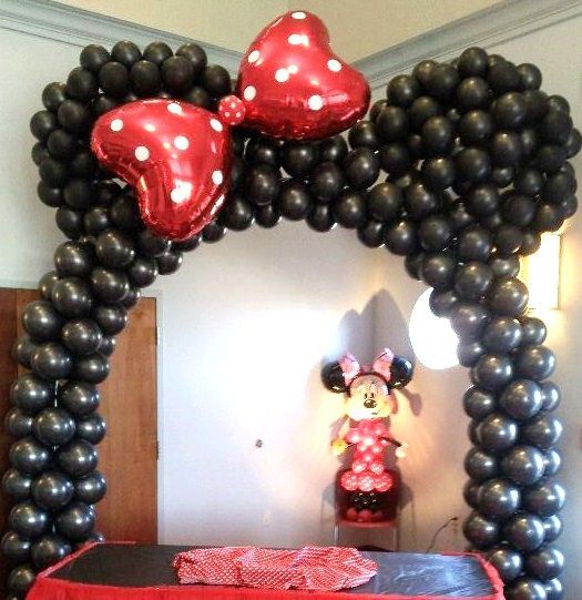 A statue of minnie mouse is behind a balloon arch