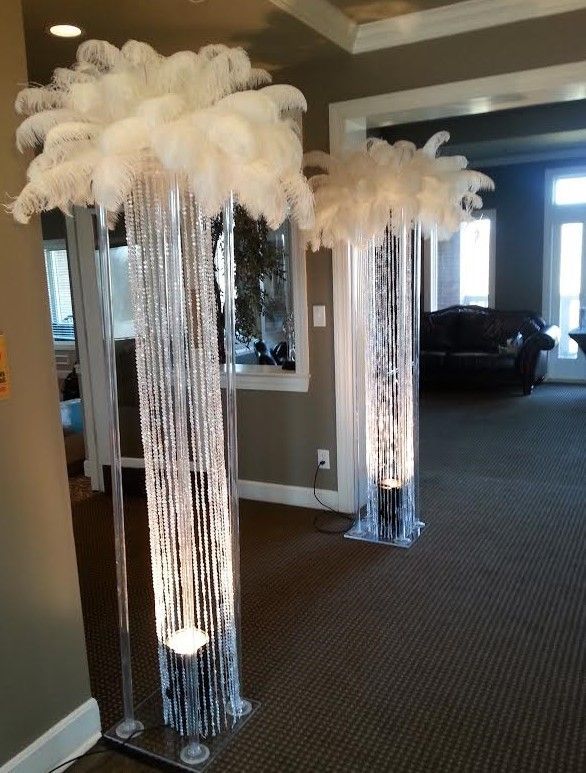 Ostrich feathers are hanging from tall clear vases in a hallway