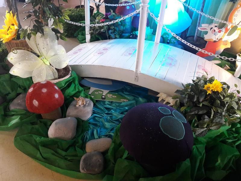 A fairy garden with a bridge , mushrooms , flowers and rocks