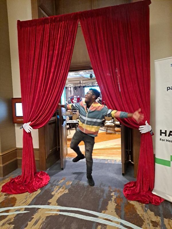 A man is opening a red curtain in a room.