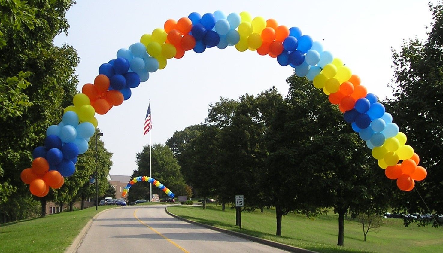A colorful balloon arch is along the side of a road