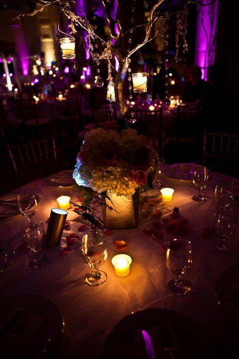 A table with candles and flowers on it in a dark room.