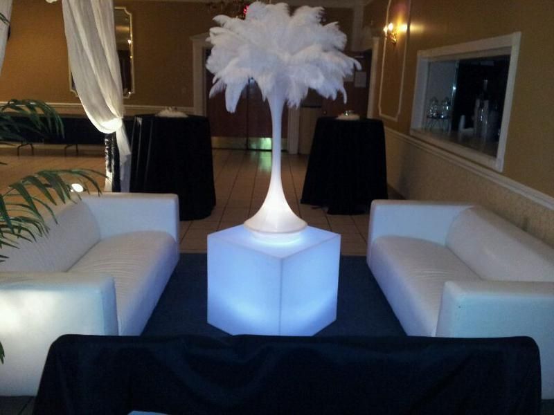 A room with a couch and a vase with feathers in it