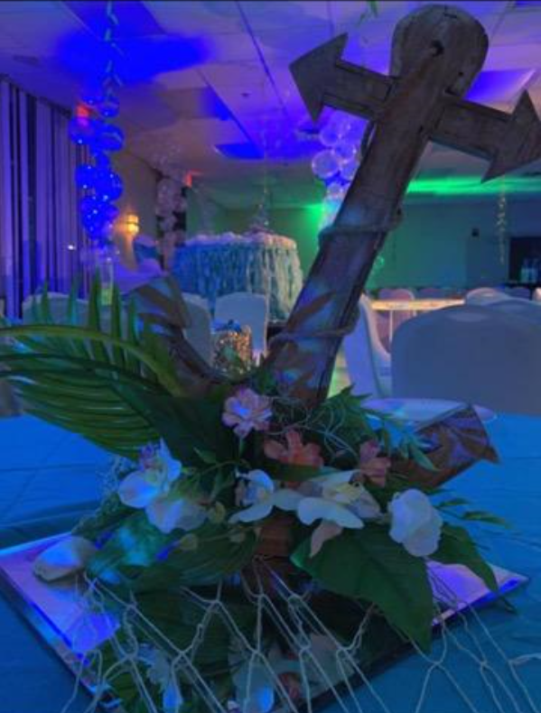 A wooden anchor is surrounded by flowers on a table.