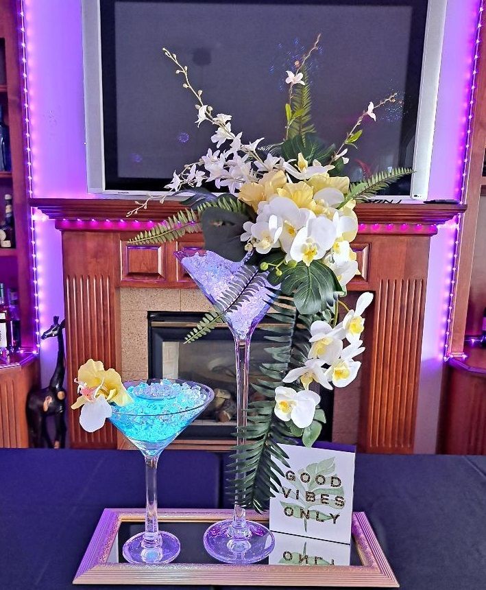 A tray with two martini glasses and flowers on it in front of a fireplace.