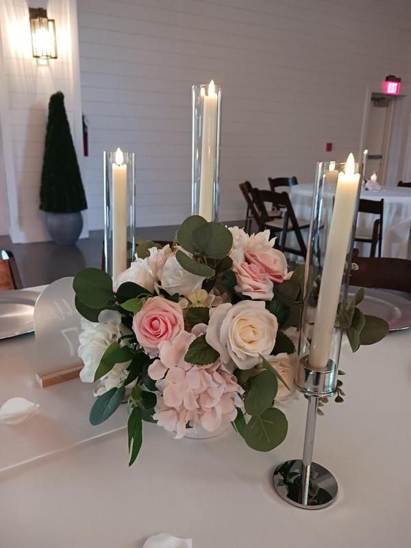 A table with a vase of flowers and candles on it.