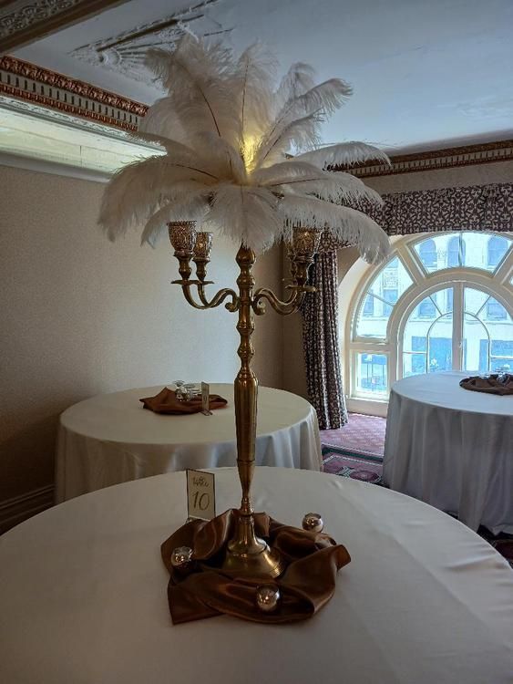 A candelabra with feathers on top of it is sitting on a table.