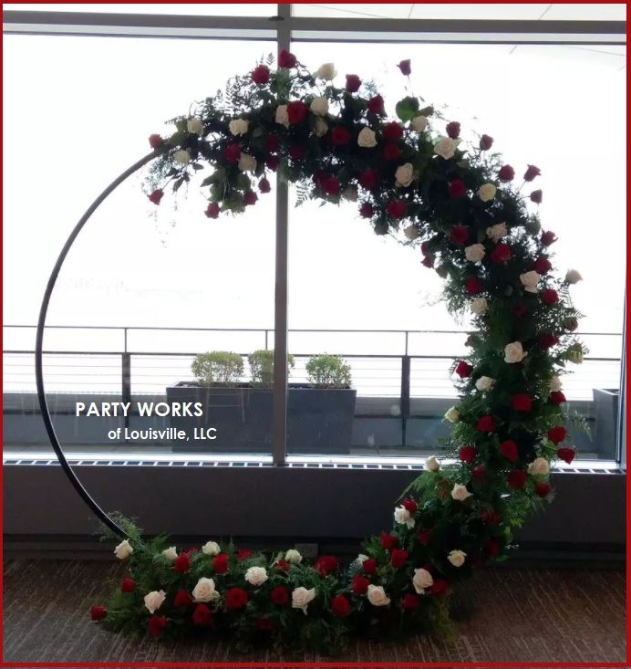 A circular arch with red and white roses and greenery by party works of louisville llc