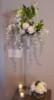 A tall vase filled with white flowers and candles on a table.