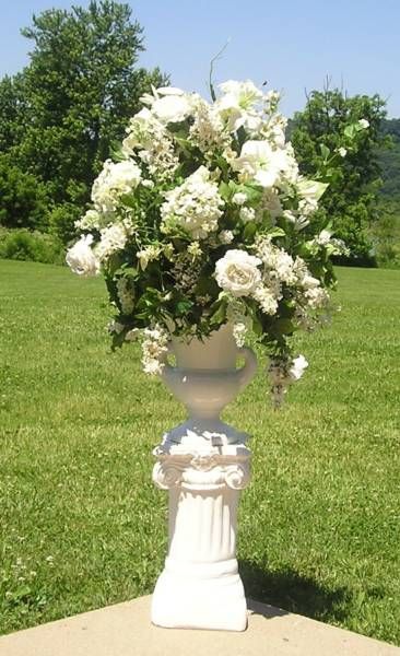 A white vase filled with white flowers on a pedestal