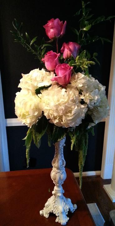 A vase filled with white flowers and pink roses on a table.