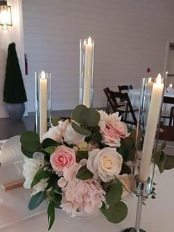 A table with a vase of flowers and candles on it.