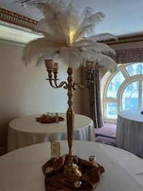 A candelabra with feathers on top of it is sitting on a table.