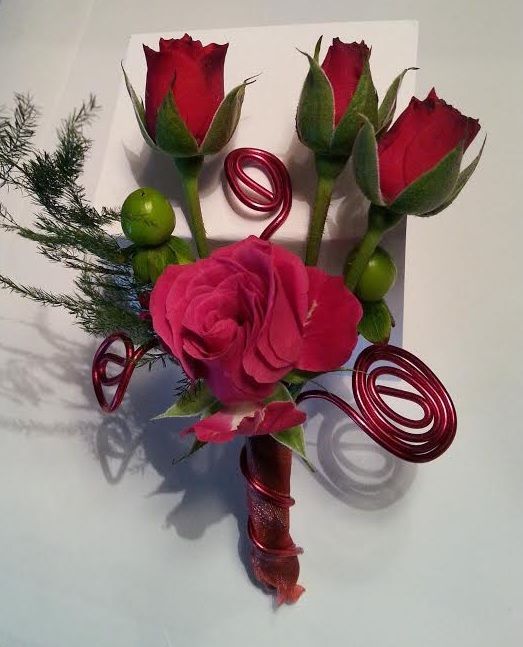 A bouquet of pink roses and green berries on a white box