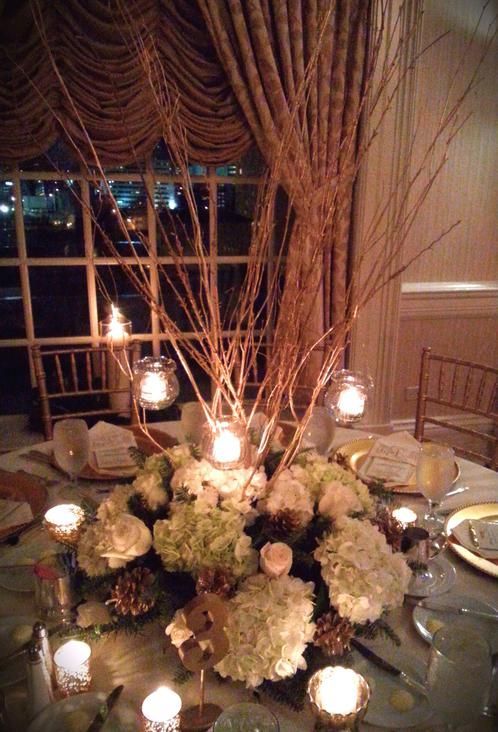 A table with a vase of flowers and candles on it.