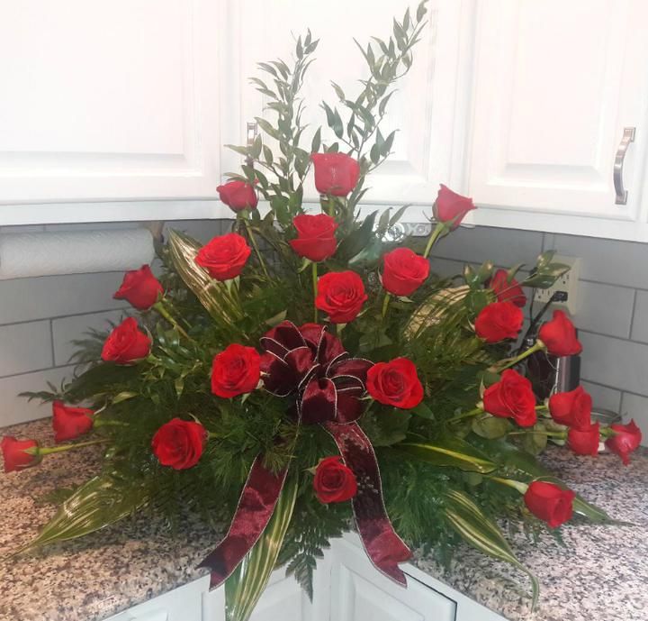 A bouquet of red roses with a burgundy bow