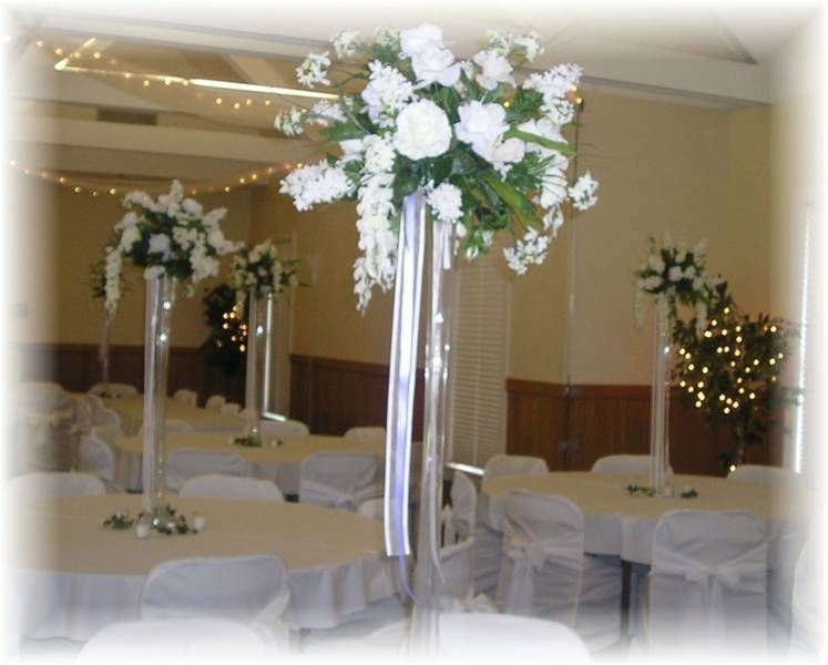 A room with tables and chairs and flowers in tall vases