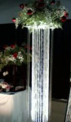 A tall clear vase filled with flowers is sitting on a table.