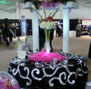 A table with a black and white table cloth and a vase of flowers on top