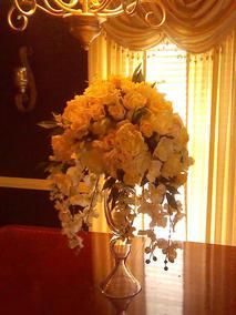 A vase filled with yellow flowers is sitting on a wooden table.