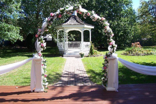 A gazebo with a floral arch in front of it