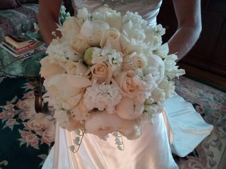 A woman in a white dress is holding a bouquet of white flowers.
