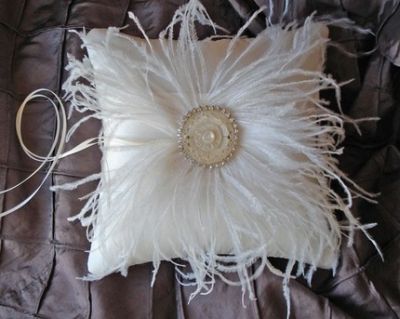 A white pillow with feathers and rhinestones on it