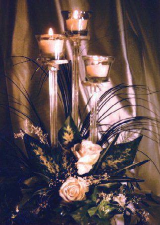 A vase filled with flowers and candles on a table.