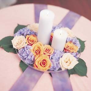 A plate of flowers and candles on a table.