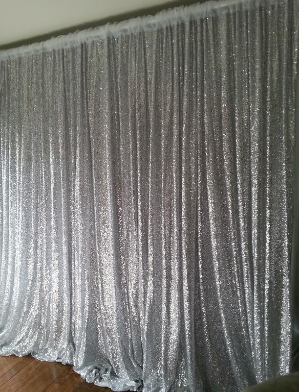 A silver sequined curtain is hanging on a wall in a room.