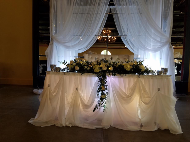 A long white table with flowers on it in a room