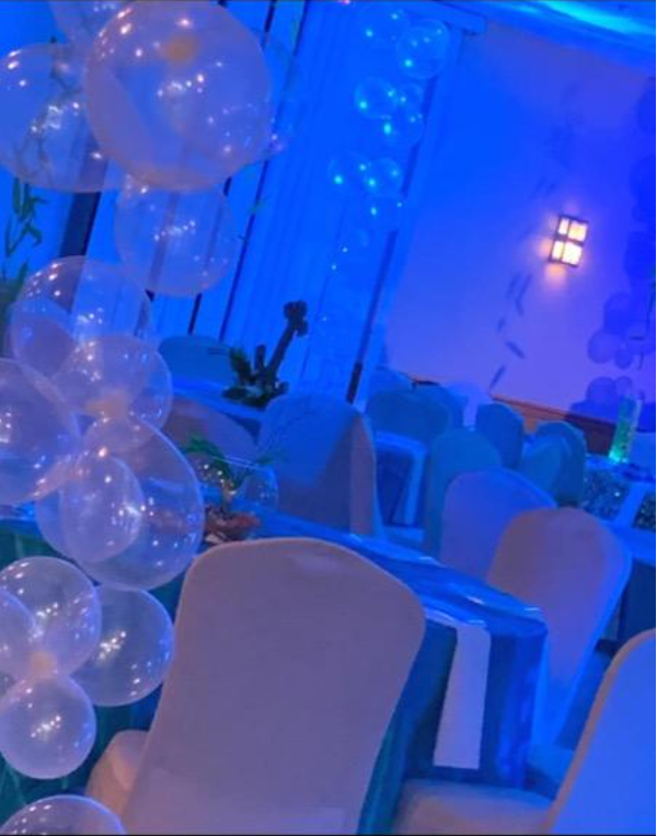 A room with tables and chairs and balloons hanging from the ceiling