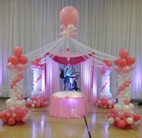 A room decorated with pink and white balloons and a table