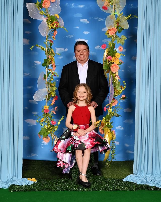 A man and a little girl are posing for a picture on a swing