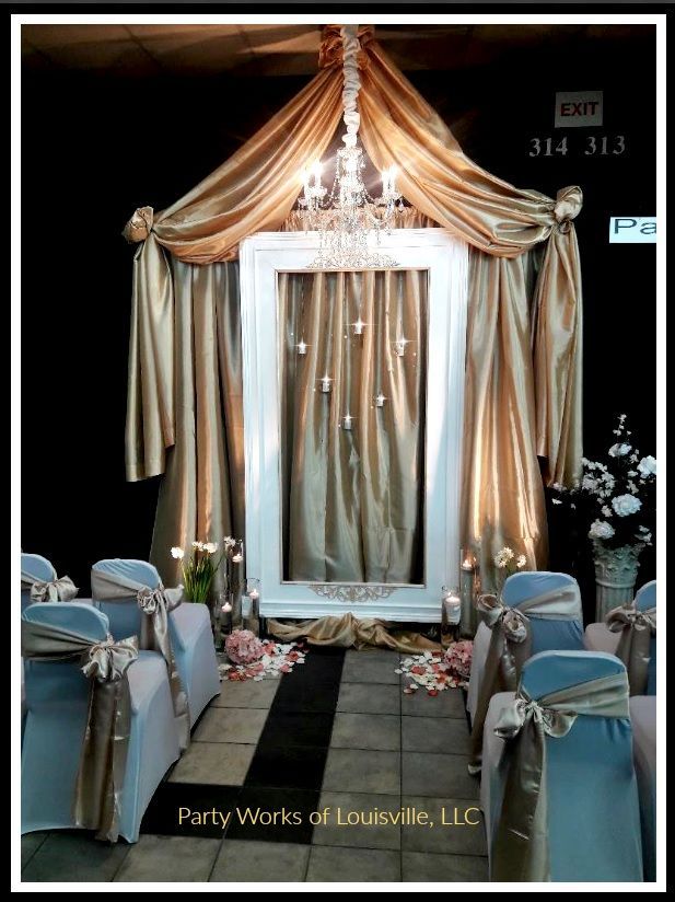 A room with chairs and a mirror with a chandelier hanging from the ceiling