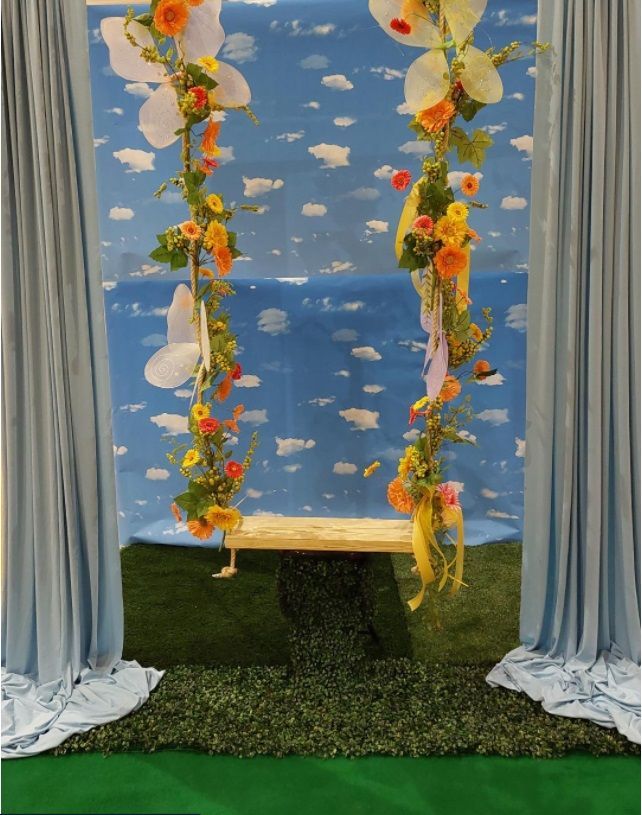A picture of a swing with flowers hanging from it
