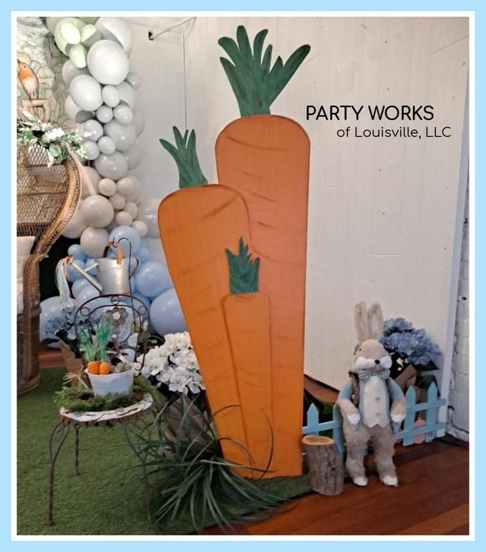 Two large carrots are displayed in front of a sign that says party works of louisville llc
