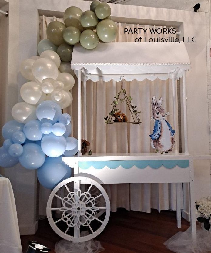 A cart is decorated with balloons and a picture of peter rabbit