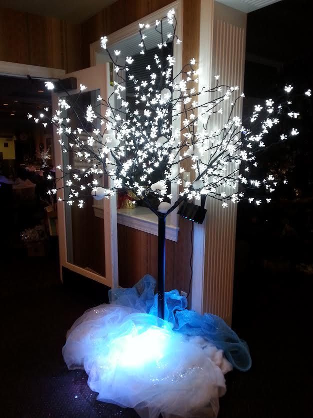 A cherry blossom tree is lit up with white lights